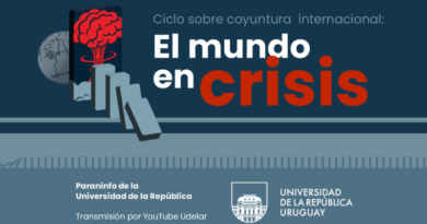 Afiche horizontal con fondo en tonos azul oscuro y gris azulado. En la parte superior, sobre un fondo azul petróleo, aparece el texto en tipografía sans serif: “Ciclo sobre coyuntura internacional:” en gris claro. Debajo, en gran tamaño: “El mundo en crisis”, donde “El mundo en” está en blanco y “crisis” en rojo intenso. A la izquierda del título hay una ilustración: un teléfono celular en posición vertical con una explosión nuclear roja en su pantalla. Detrás del celular se ve el contorno de america sobre un globo terraqueo en gris claro con líneas dibujadas, y delante una serie de fichas tipo dominó en tonos grises que caen en diagonal hacia la derecha, sugiriendo efecto en cadena. Una línea horizontal clara atraviesa la imagen separando la parte superior de la inferior. En la franja inferior, sobre fondo gris azulado, aparece a la izquierda: “Paraninfo de la Universidad de la República” Debajo: “Transmisión por YouTube Udelar” A la derecha se ubica el logo institucional (el edificio central estilizado dentro de un escudo) junto al texto: “UNIVERSIDAD DE LA REPÚBLICA URUGUAY” La composición combina contraste entre azul, blanco y rojo, con una estética sobria y simbólica que remite a crisis global y efecto dominó.